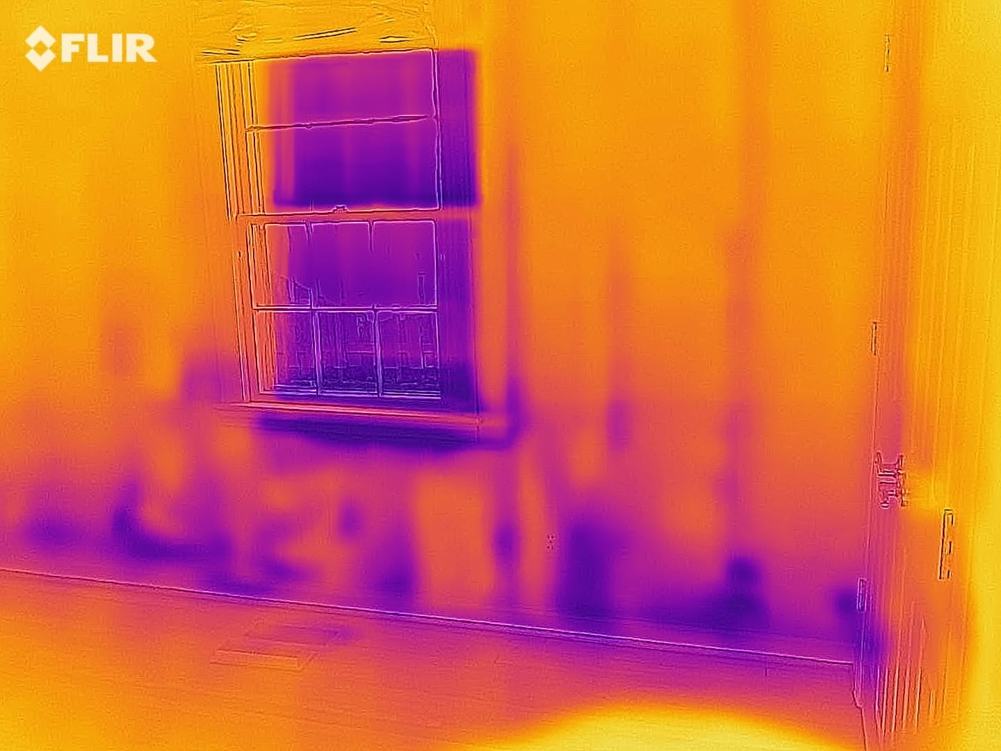 Thermal image showing temperature patterns around a window and lower wall